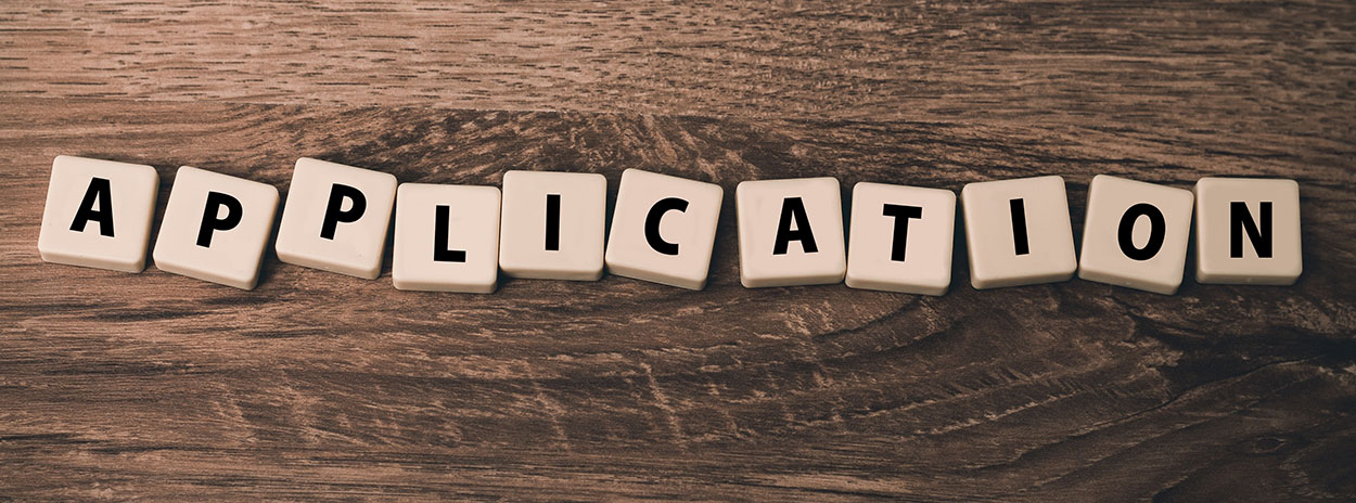Word "Application" spelled out using Scrabble tiles.
